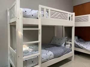 a couple of white bunk beds in a room at Rest N Ramble Hostel Near ADCB Metro Station in Dubai