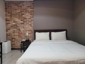 a bedroom with a white bed with a brick wall at Romio Motel in Gwangju