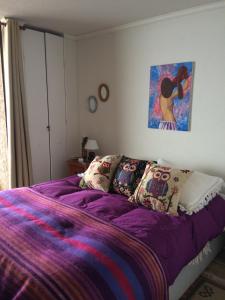 a bedroom with a bed with purple sheets and a painting at Papudo, vista despejada, condominio Vistamar. in Papudo