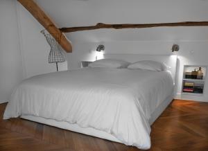uma cama branca num quarto branco com piso em madeira em Loft dans le clocher face au chateau em Bonnelles