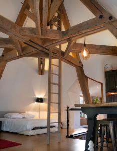 um quarto com uma cama, uma escada e uma secretária em Loft dans le clocher face au chateau em Bonnelles