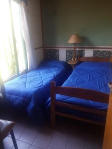 two beds with blue sheets in a room at Cabañas del Sol in Vista Flores