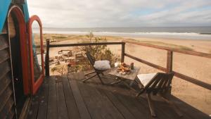 a wooden deck with chairs and a table on the beach at Narakan Cabo Polonio in Cabo Polonio