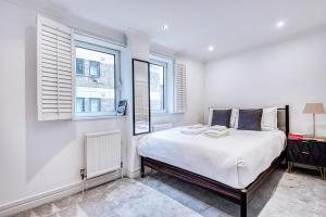 a bedroom with a bed and two windows at Stunning Apartment in Fashionable Marylebone in London