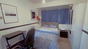 a bedroom with a bed and a desk and a chair at Cozy Room in London in Plumstead