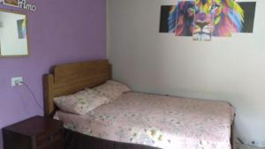 a small bedroom with a bed and a painting on the wall at Casa Cláudio Rambo in Ilhabela