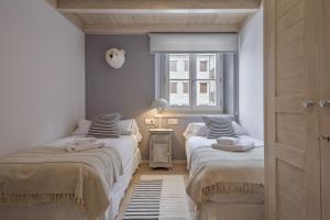 Duas camas num pequeno quarto com uma janela em Luderna - Apartamento Val de Ruda B22 Tuc Ermer em Baqueira-Beret