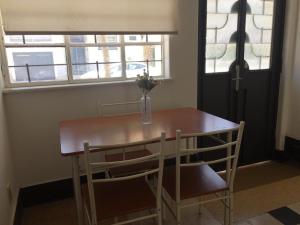 einen Esstisch mit 2 Stühlen und eine Vase mit Blumen in der Unterkunft Artistes du Monde in Montevideo