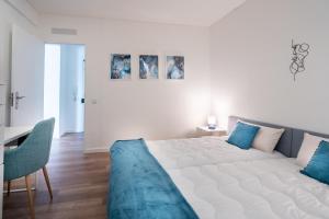 ein Schlafzimmer mit einem großen weißen Bett mit blauen Kissen in der Unterkunft HM - HouseMirage in Paço de Arcos
