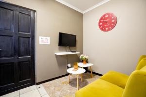 a living room with a yellow couch and a clock at URlyfstyle Cottage 10km from OR Tambo Int Airport in Kempton Park
