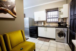 a kitchen with a washing machine and a yellow chair at URlyfstyle Cottage Near OR Tambo International Airport in Kempton Park