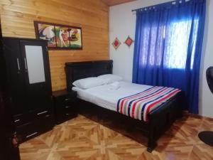 Schlafzimmer mit einem Bett und einem Fenster mit blauen Vorhängen in der Unterkunft Alojamiento Monik in Ríohacha