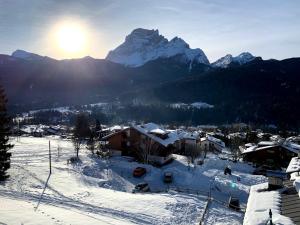 een met sneeuw bedekt dorp met bergen op de achtergrond bij Ca' del Sole in San Vito di Cadore