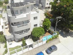 an overhead view of a white apartment building with a swimming pool at Residencial Tia Dilma in Bombinhas
