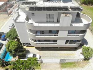 an aerial view of a white apartment building with a swimming pool at Residencial Tia Dilma in Bombinhas