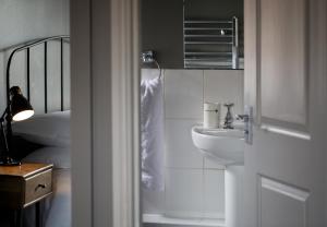Baño blanco con lavabo y espejo en The Duke William, en Littlebourne