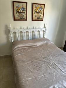 a bed with a white bedspread and two pictures on the wall at Apart Momias del Llullaillaco II Anexo Av. Belgrano in Salta
