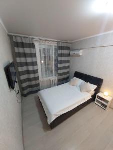 a small bedroom with a bed and a window at Отличная квартира со всеми удобствами. in Almaty