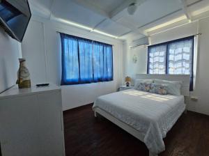 a bedroom with a bed and a blue window at Blue House Joyuda in Cabo Rojo