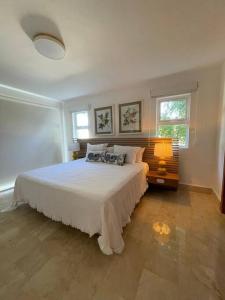 - une chambre avec un lit blanc et 2 fenêtres dans l'établissement Casa Coral - The Coral House, à San Felipe de Puerto Plata