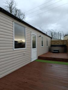 a small house with a porch and a patio at Hillingworth's Hot Tub Retreat - Lochmaben in Dumfries