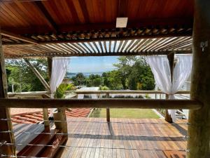 een uitzicht vanaf het terras van een huis met witte gordijnen bij Santomar Guest House in Ilhabela