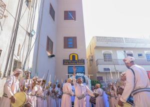 Un groupe de personnes en costumes debout dans une parade dans l'établissement فندق المدينة القديمة Old Town Hotel, à Nizwa