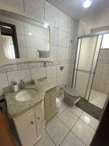 La salle de bains est pourvue d'un lavabo, de toilettes et d'une douche. dans l'établissement AP de praia com sacada, churrasqueira e garagem, à Balneário Camboriú
