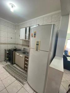 - une cuisine équipée d'un réfrigérateur blanc dans l'établissement AP de praia com sacada, churrasqueira e garagem, à Balneário Camboriú