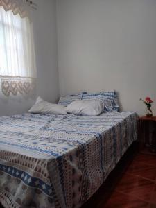 a bedroom with a bed with a blue and white blanket at Canastra Hostel e Camping - quartos in Vargem Bonita
