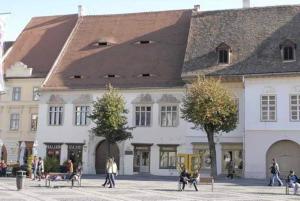 a large building with people sitting on benches in front of it at Apartament Sophie in Sibiu +7 photos