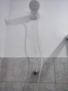 a shower head with a hose coming out of a tub at Canastra Hostel e Camping - quartos in Vargem Bonita
