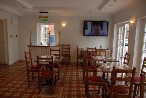 a dining room with tables and chairs and a tv on the wall at Balham Lodge in London