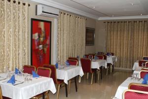 a dining room with white tables and red chairs at Hotel Residence Flamani in Lomé
