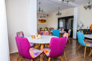 a dining room with a table and colorful chairs at VILA LUCA-Hotel in Şirnea