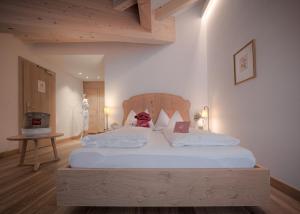 a bedroom with a large white bed with a wooden headboard at Il Tyrol in San Candido