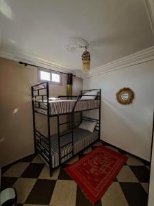 2 Etagenbetten in einem Zimmer mit einem karierten Boden in der Unterkunft taghazout life Guest House in Taghazout