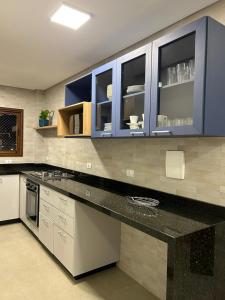 a kitchen with blue cabinets and a black counter top at Apto 302 Edifício Manoel Teixeira in Arroio do Silva