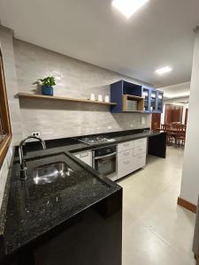 una cocina con encimera negra y fregadero en Apto 302 Edifício Manoel Teixeira, en Arroio do Silva