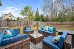a patio with blue couches and a table and a fence at NEW Victorian Theme, 3BR, LRG Backyard close to PNC Arena, Downtown, and RDU Airport in Raleigh