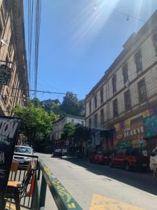 una calle de la ciudad con coches estacionados al costado de la carretera en Hostal Casa Alegre en Valparaíso
