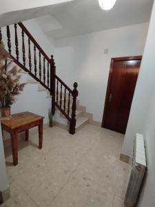 pasillo con escalera y mesa de madera en Casa Vitoria, en Monroyo