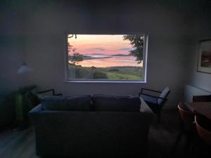 ein Wohnzimmer mit Couch und großem Fenster in der Unterkunft Curlew Cottage in Beltra