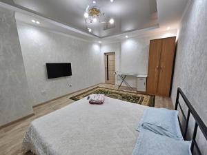 a bedroom with a bed and a flat screen tv at 2 комнатная квартира in Aktobe