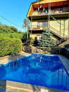 una gran piscina azul frente a una casa en Villa Qeroli Saguramo en Saguramo