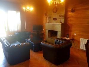 sala de estar con 2 sillas de cuero y chimenea en Villa Qeroli Saguramo en Saguramo