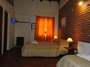 Habitación de hotel con 2 camas y pared de ladrillo en Hostería Las Lomas en Cortaderas