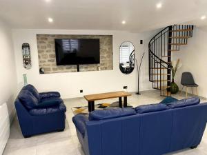 a living room with a blue couch and a tv at Maison pour séjour in Mouzay
