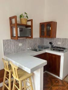 a kitchen with a counter and a sink and chairs at El Encanto de Mimi in Puerto Ayora