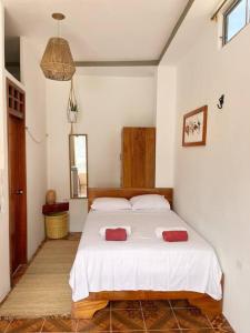 1 dormitorio con 1 cama con 2 almohadas rojas en El Encanto de Mimi, en Puerto Ayora
